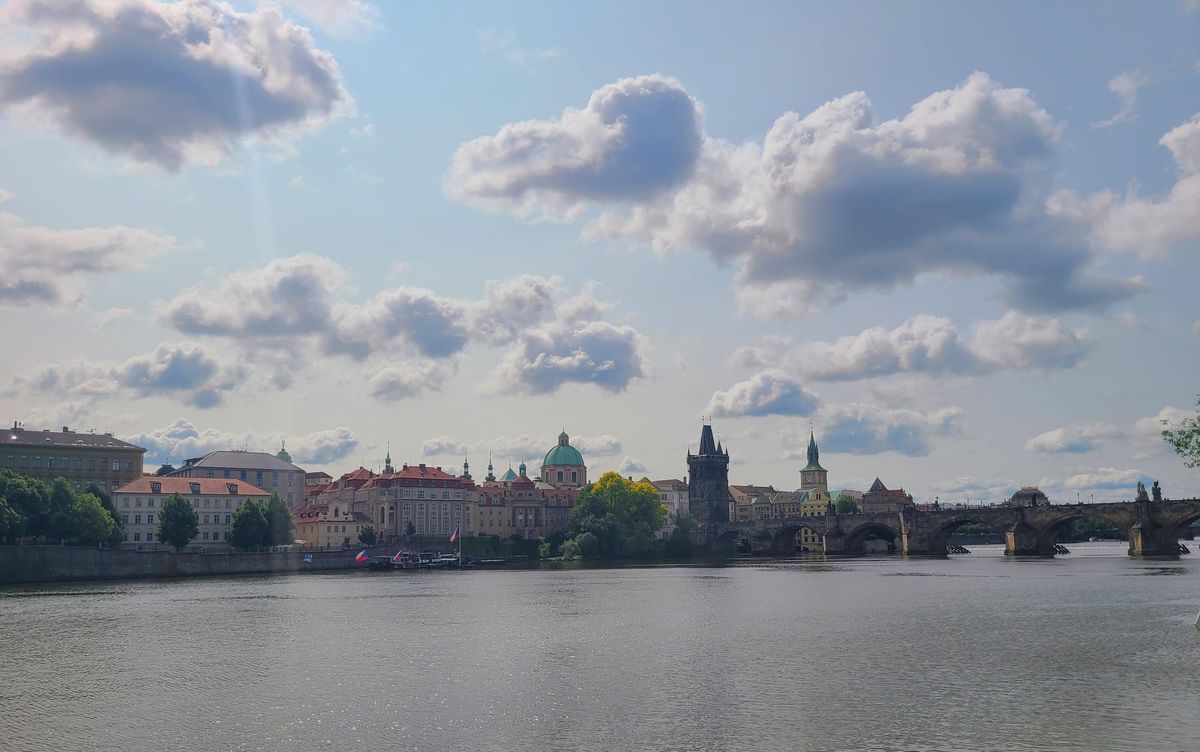 Prague, Czech Republic, city line, including the Charles Bridge, from across the Vltava River. Clouds float across the sky.