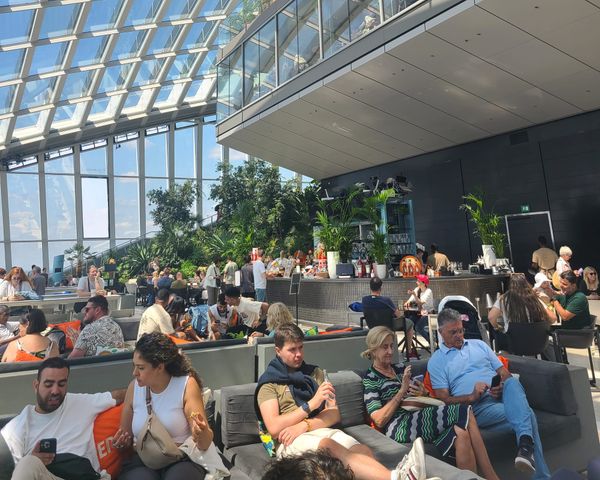 People sitting in a lounge bar inside an indoor garden.