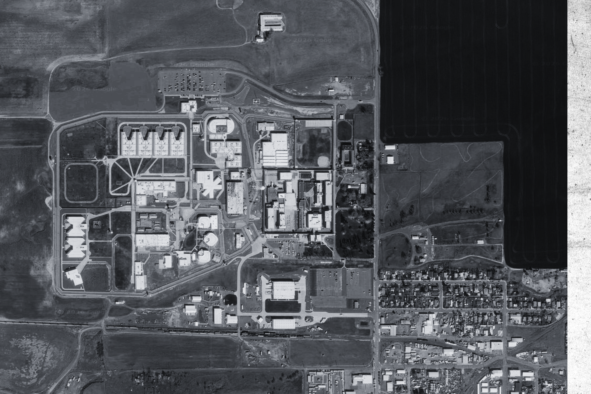 A prison next to train tracks and a small city.