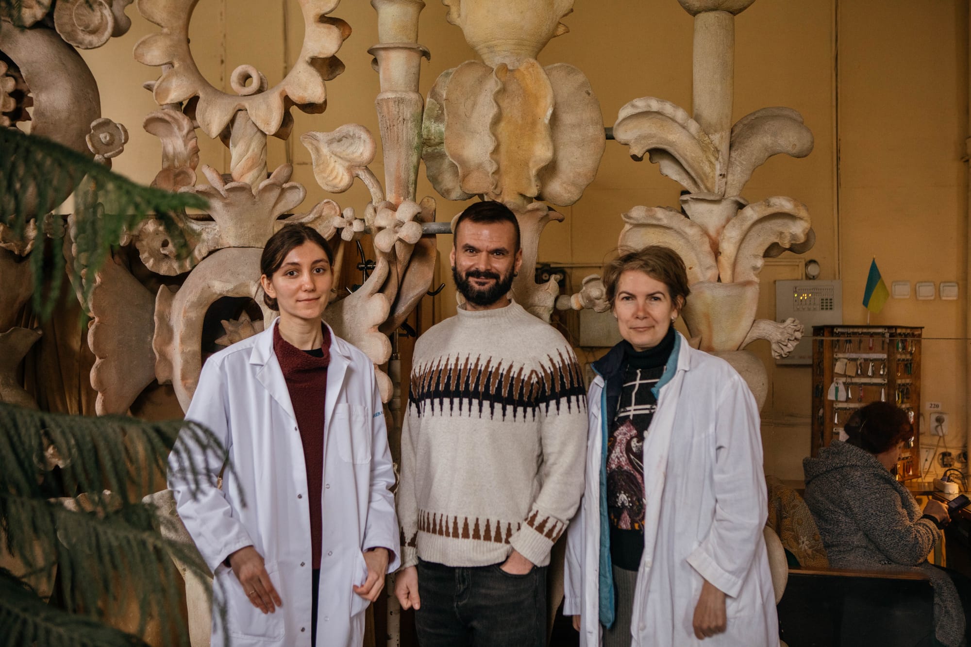 A brown-skinned researcher in a sweater stands in the middle. To his left and right are two female researchers in lab coats.