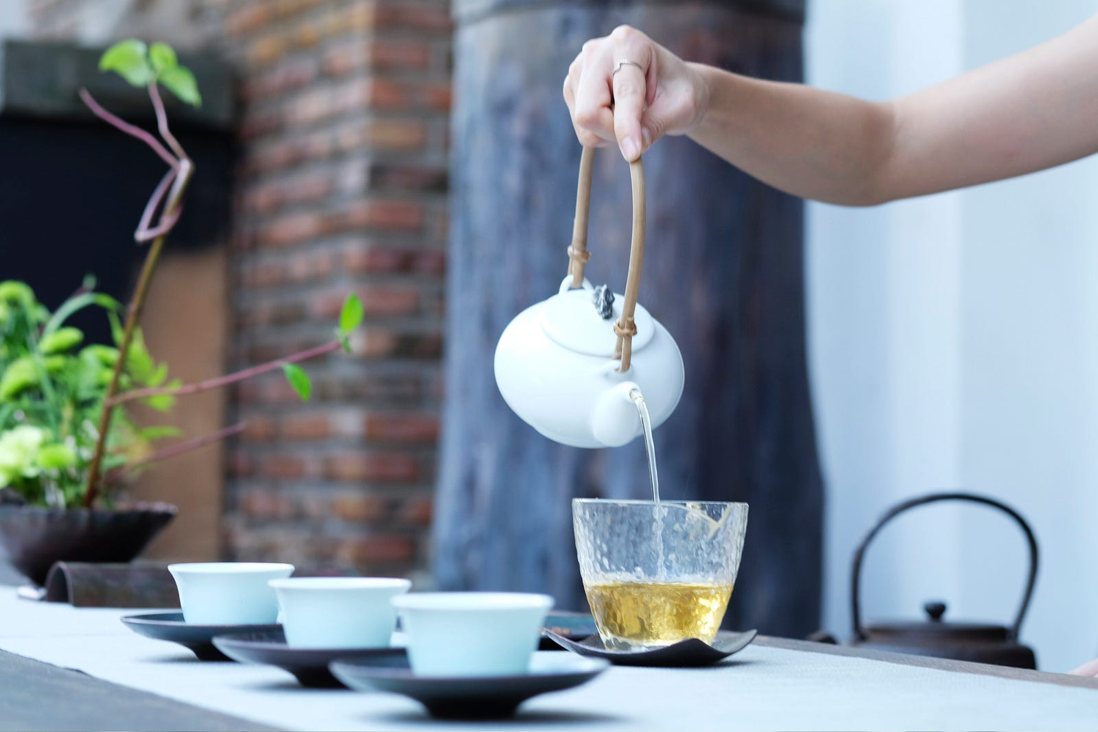 A person pouring tea into a glass cup.