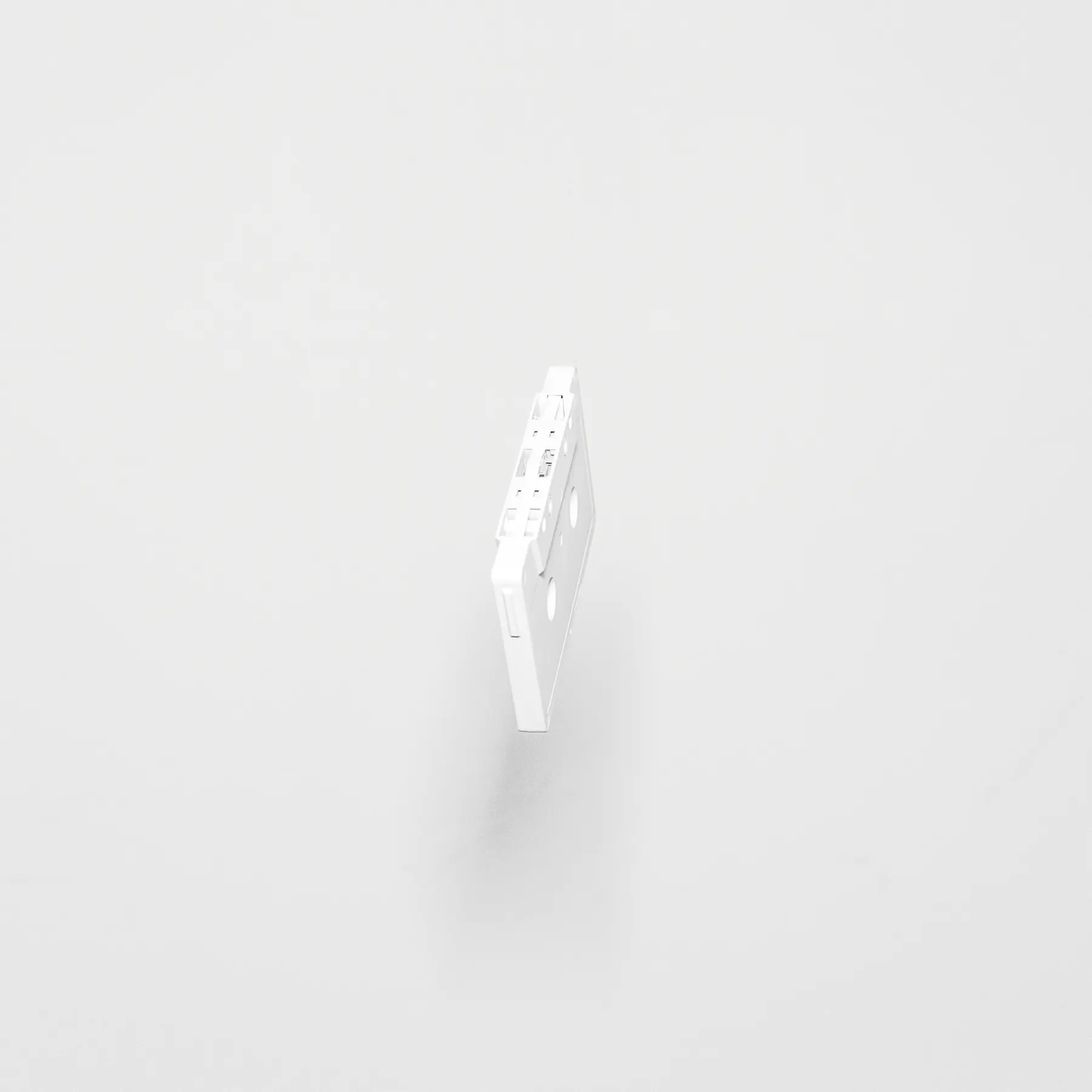 A white coloured casette is seen on a plain white wall. 