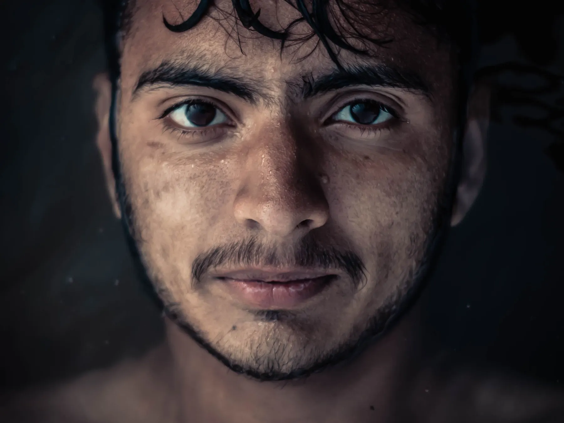 Moody close-up portrait of a South Asian man with wet hair in Srinagar.