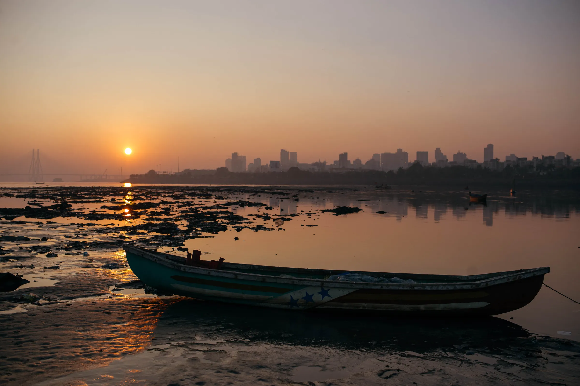 A view of fishing boats at sunset along the polluted Mumbai coast