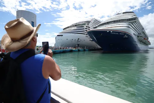 A tourist takes a photo of the cruise Carnival Magic 