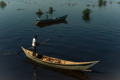 A man rows a boat while standing