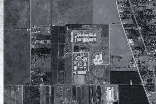 Aerial view of a large women's prison next to fields and a country road.
