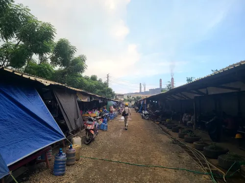 A worker walks in a corridor. To both sides of him are taps and tin roof shelters.