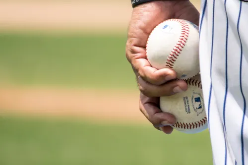 A player holds two major league base balls in one hand.