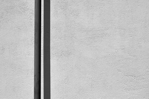 A rod and its shadow are seen against a plain wall.