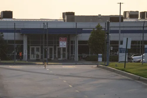 Workers walk through the parking lot of a fenced data center.