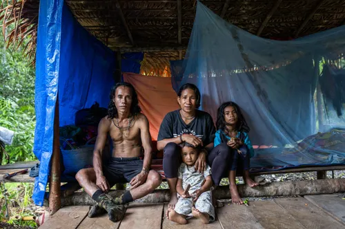 Four Indigenous people sit in a hut