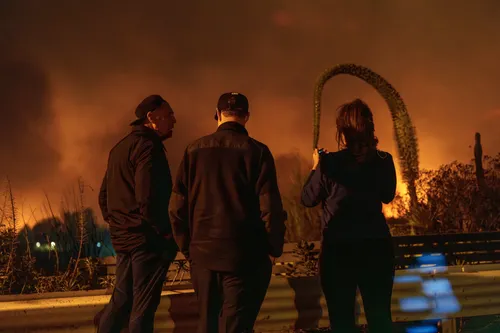 Three residents observe a large wildfire.