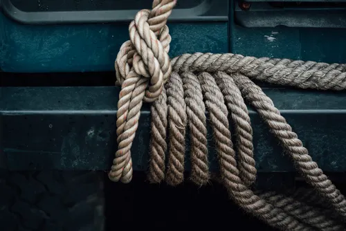 A blue surface resembling part of a vehicle has a piece tied to it with twine.