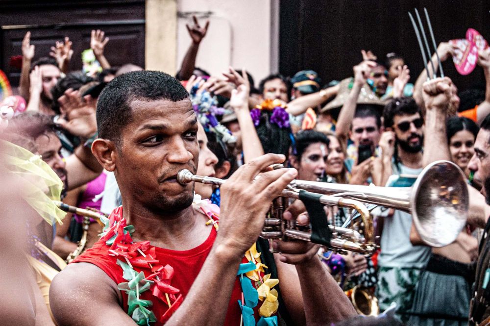 homem negro em bloco de carnaval tocando instrumento de supro de metal