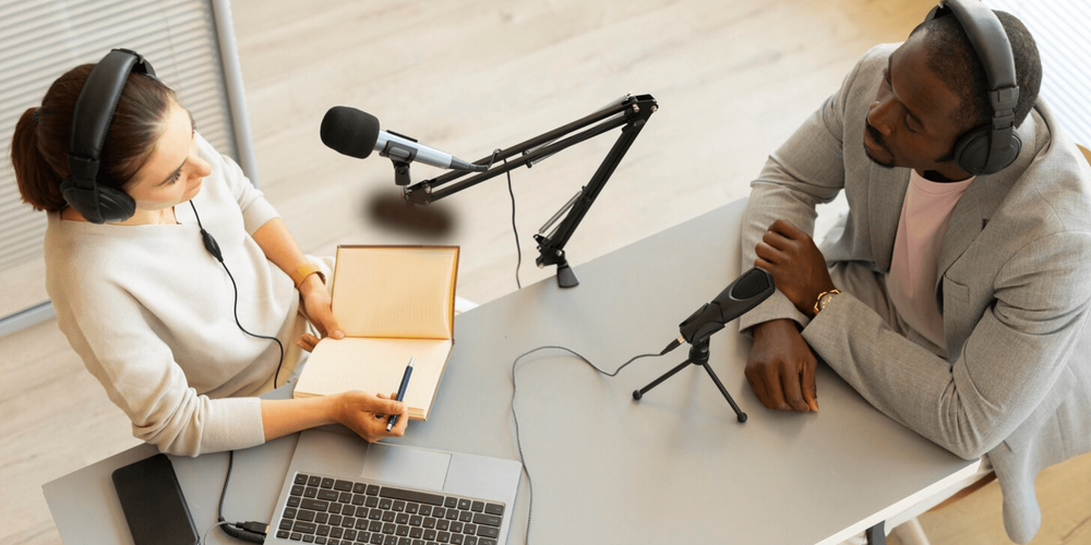 Foto superior de uma mesa de gravação de podcast com uma dupla de apresentadores.