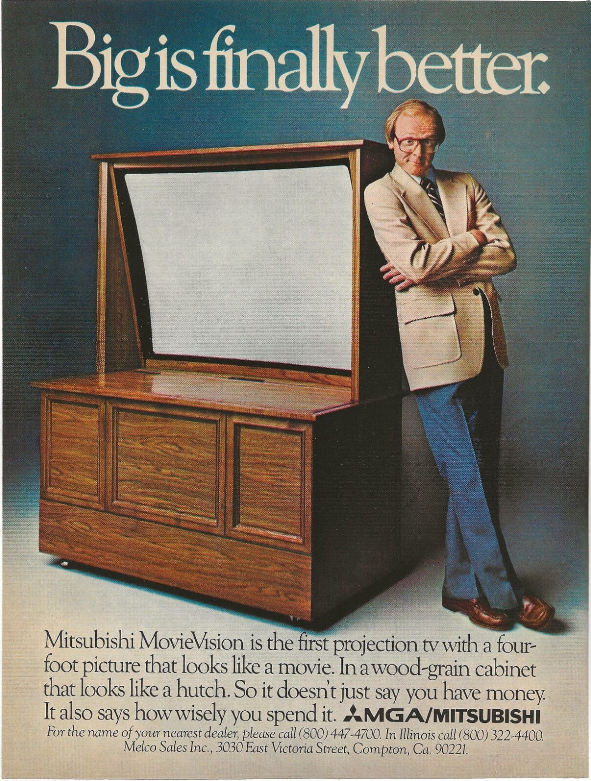 A smug looking white nerd leans next to a comically big wooden Mitsubishi TV cabinet.