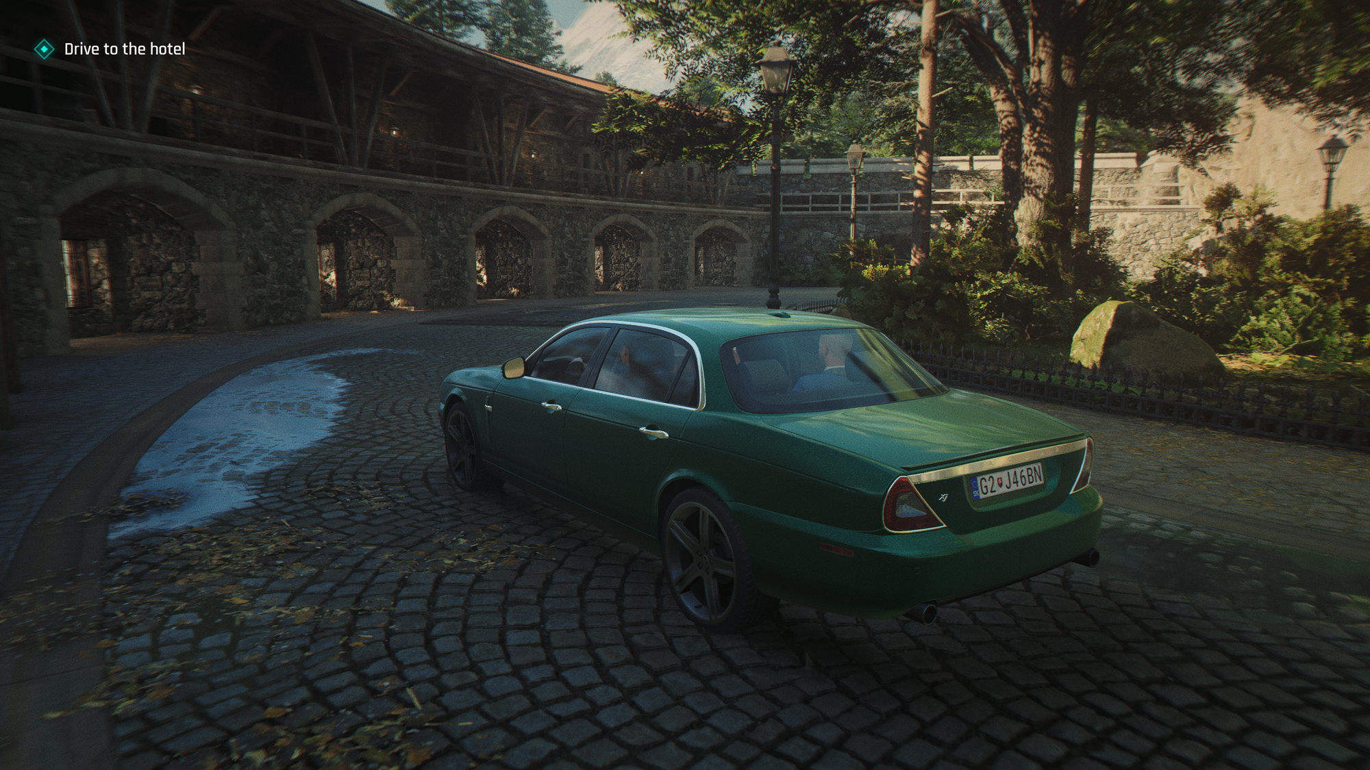 A green Jaguar makes a sweeping turn across a cobbled driveway
