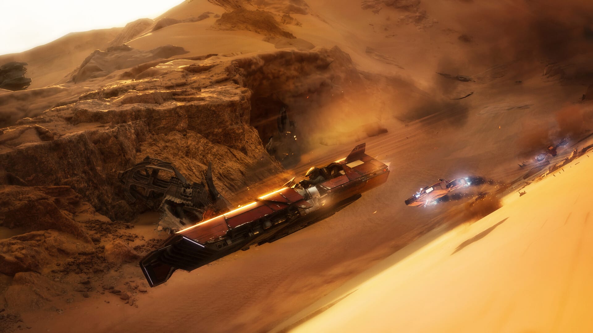 Dust is stirred against the walls of a canyon as three speeders blast past wreckage embedded in the ground.