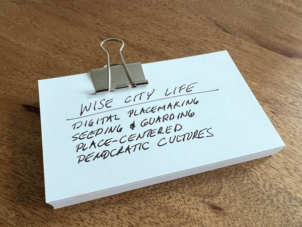 Thick note cards in a silver spring steel binder clip, on a warm-hued solid wood table top.
