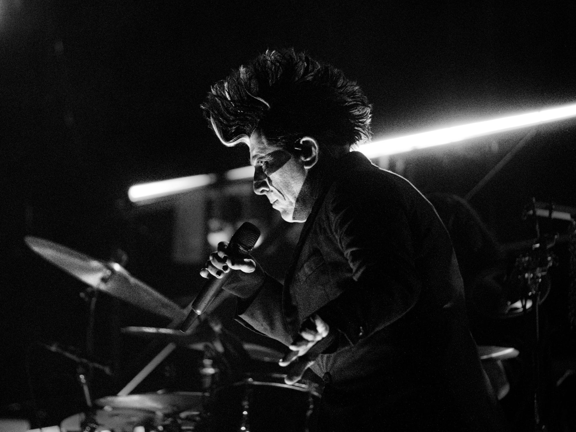 Maynard James Keenan looking at the crowd with a serious expression, one hand extended to his side (towards the camera). 
