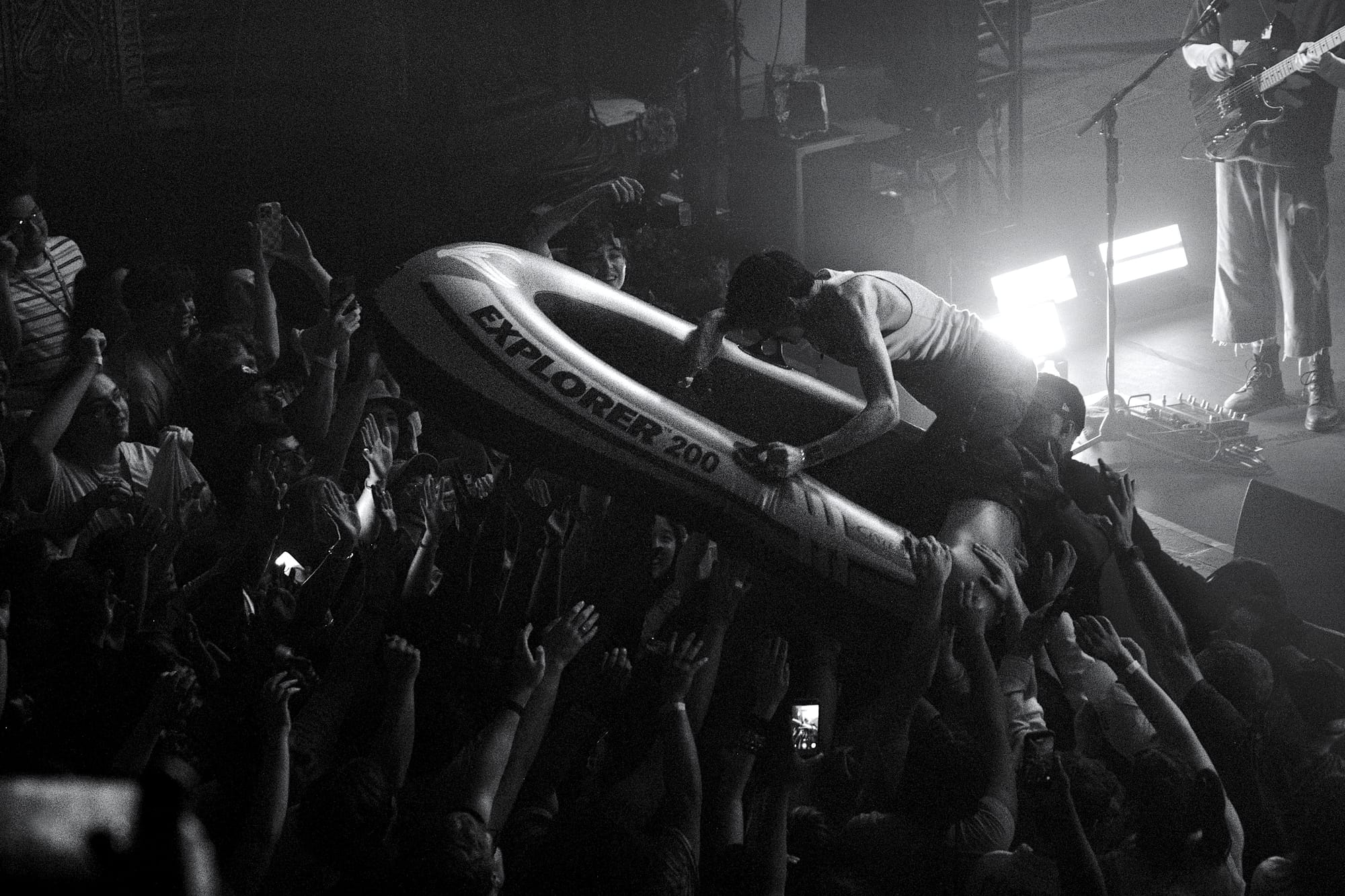 The lead singer of Good Kid climbing into an inflatable raft while being held up by security and audience members.