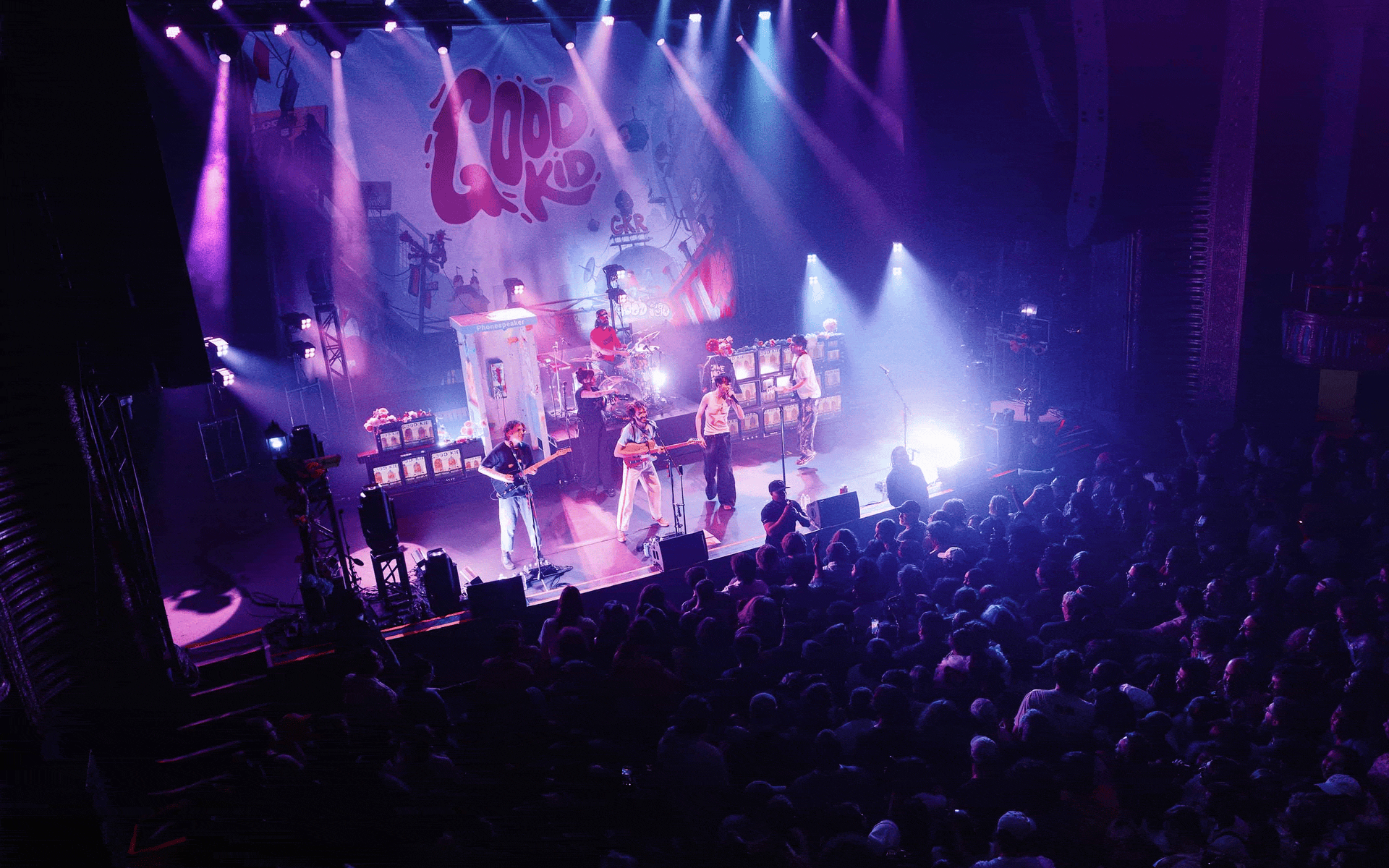 A gif of Good Kid performing to the crowd, with flashing strobe lights from above the stage.
