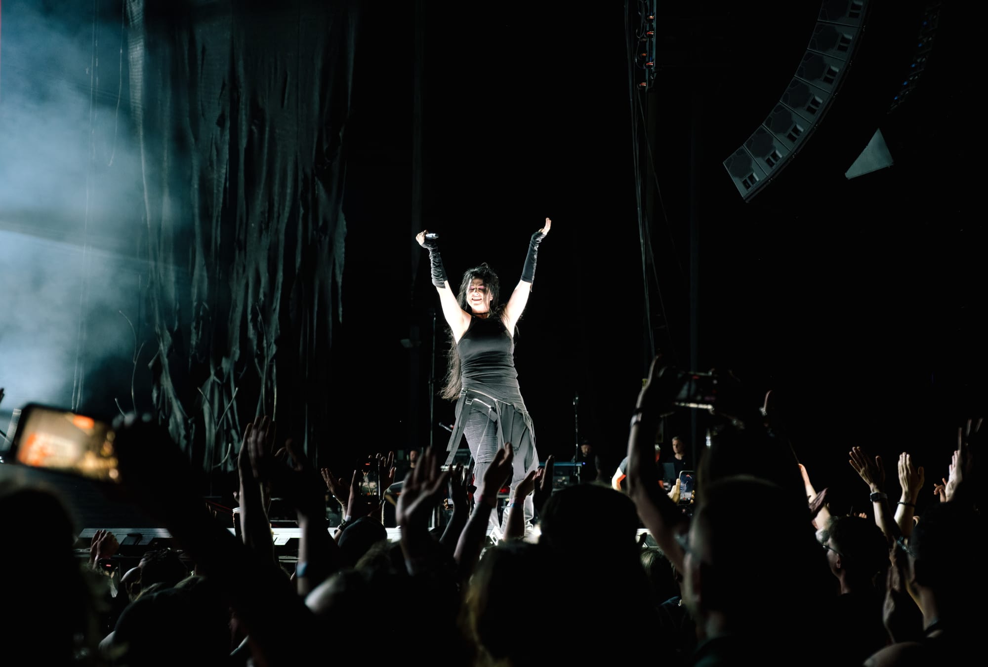 Amy Lee standing with her arms extended into the air over her head, seemingly mimicking the excited extended arms of fans in front of her.