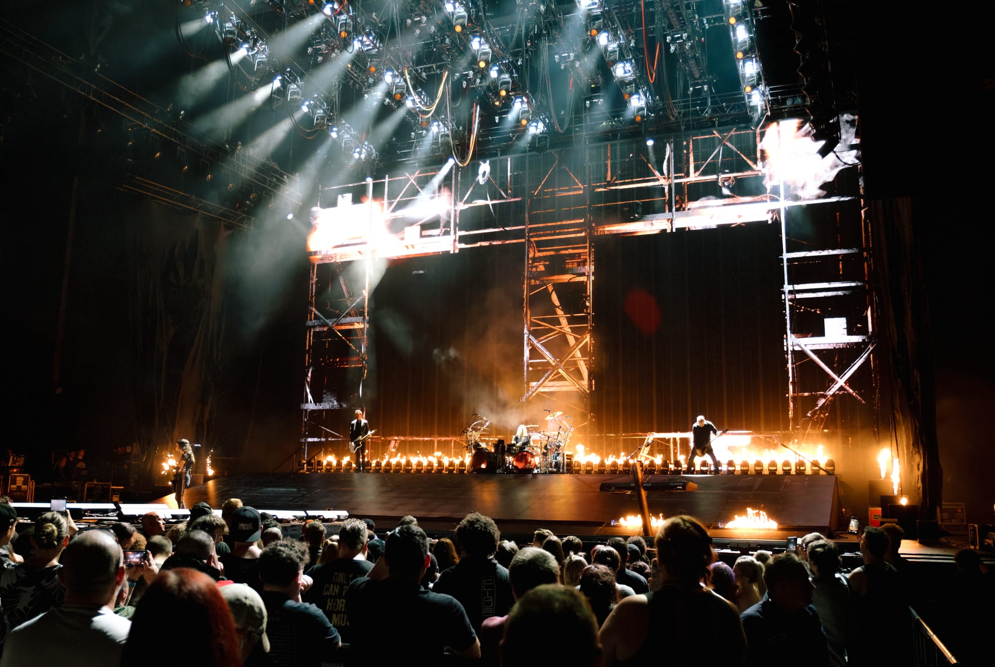 The stage Evanescence performed on, lit by fire and bright white stage lighting. The crowd can be seen looking onwards, with the tops of their heads lit by the stage lighting.