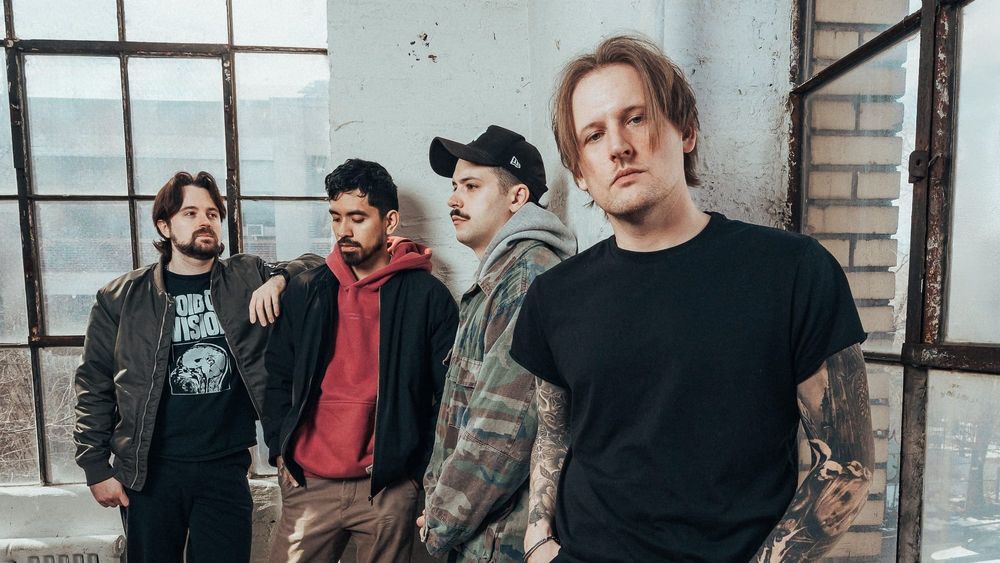 Photo of the four members of the band Advents in an industrial-style room. 