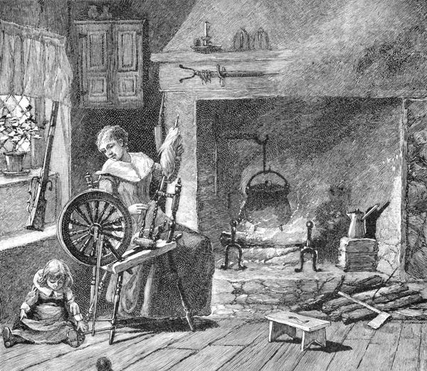 A woman spinning at a wheel beside a colonial hearth, with a child seated on the floor nearby and a kettle suspended over an open fire.