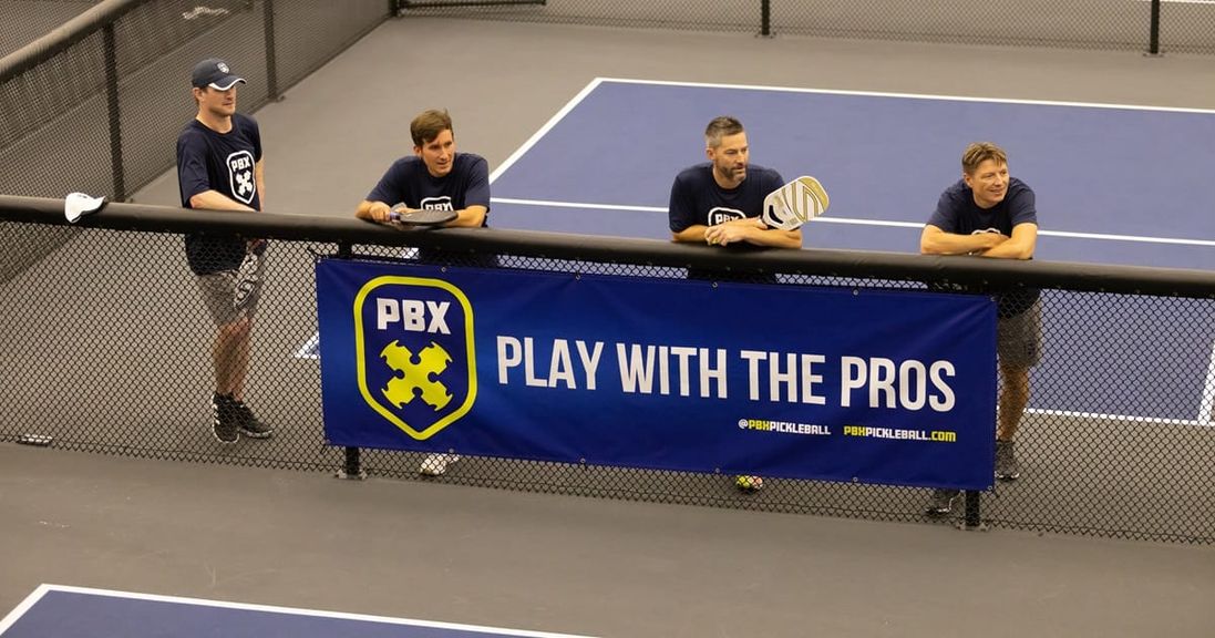 
                                        PBX pickleball league participants stand courtside.
                                    