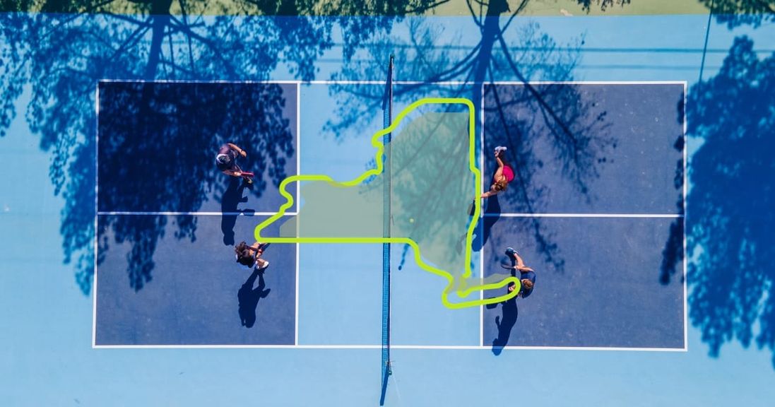 
                                        Outline of New York set against an active pickleball court.
                                    