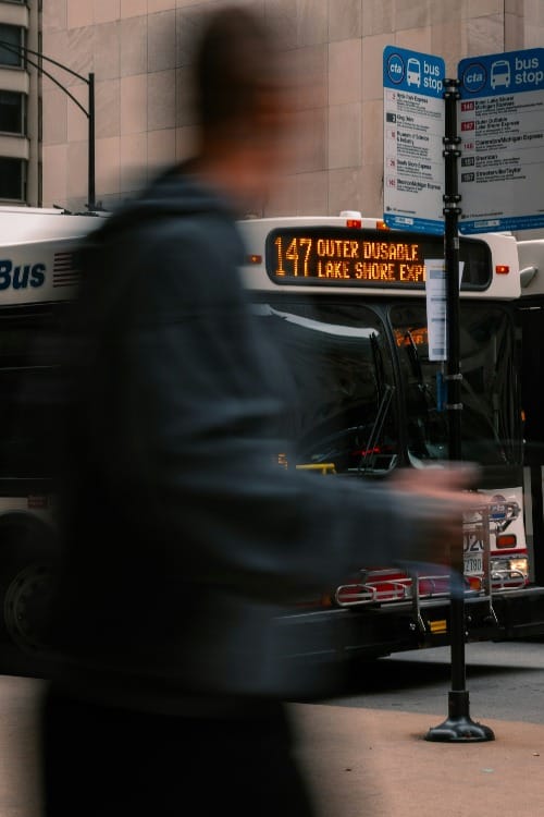 A blurred person walks past a chicago bus stop.