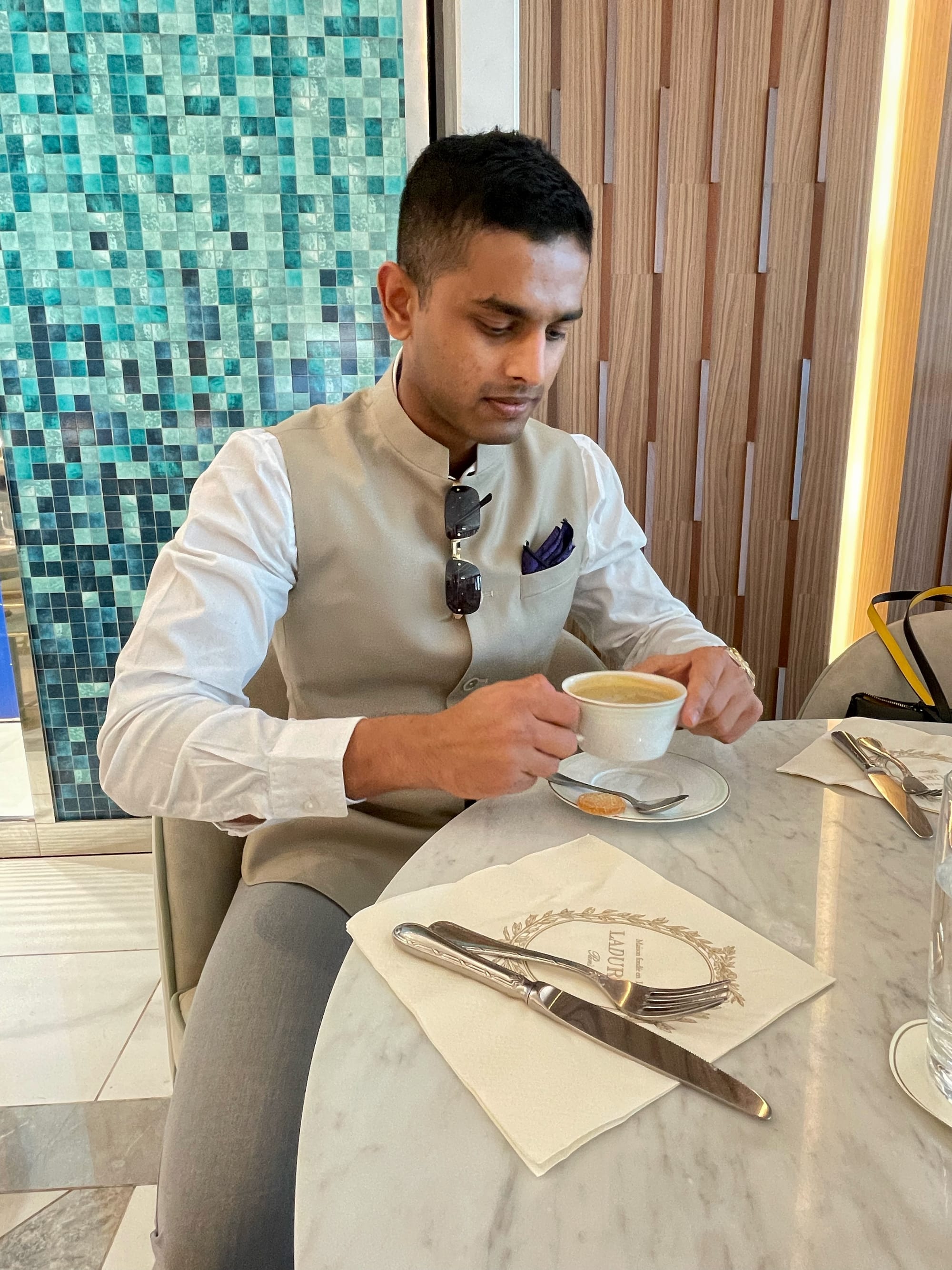 Image of Yash Chavan dressed eleganlty, drinking coffee in Mumbai.