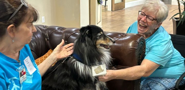 Photo of a dog sitting between two women.
