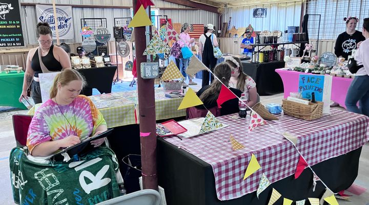 Photo of a farmers market booth that specializes in caricatures and face painting.