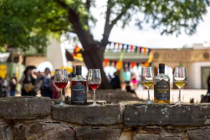 Bottles of mead and glasses are on display at a festival. 