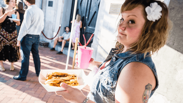 Deanna on her wedding say holding a pink solo cup and two chili cheese dogs outside Gallery 5