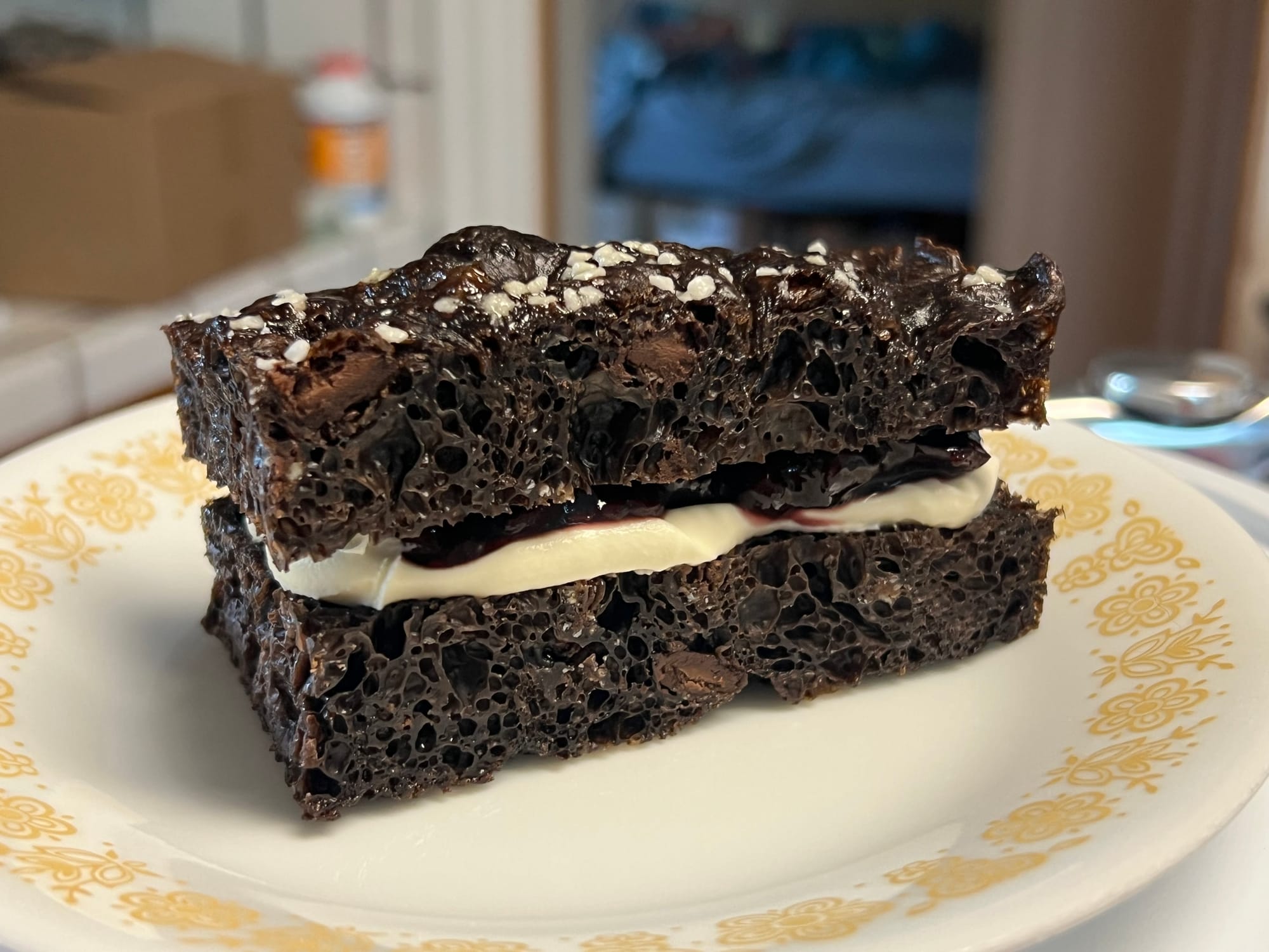 A very dark brown, almost black, focaccia, with white, creamy mascarpone and deep red cherry jam in the middle.