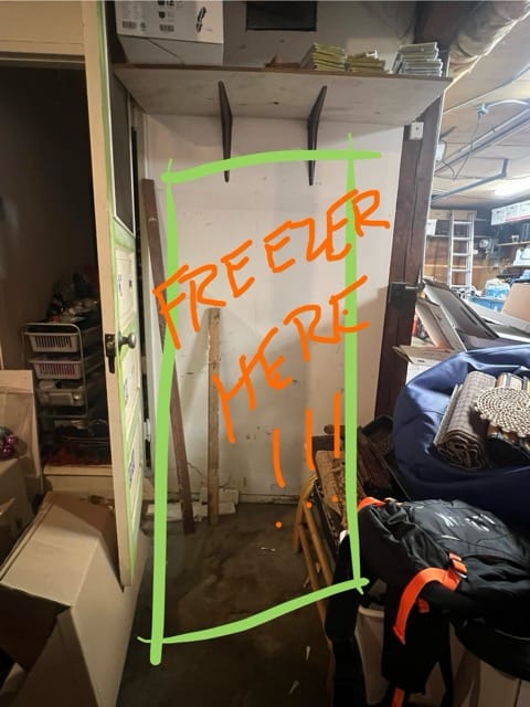 Photograph of an almost-cleared spot in the garage, with text overlay saying "freezer here!"