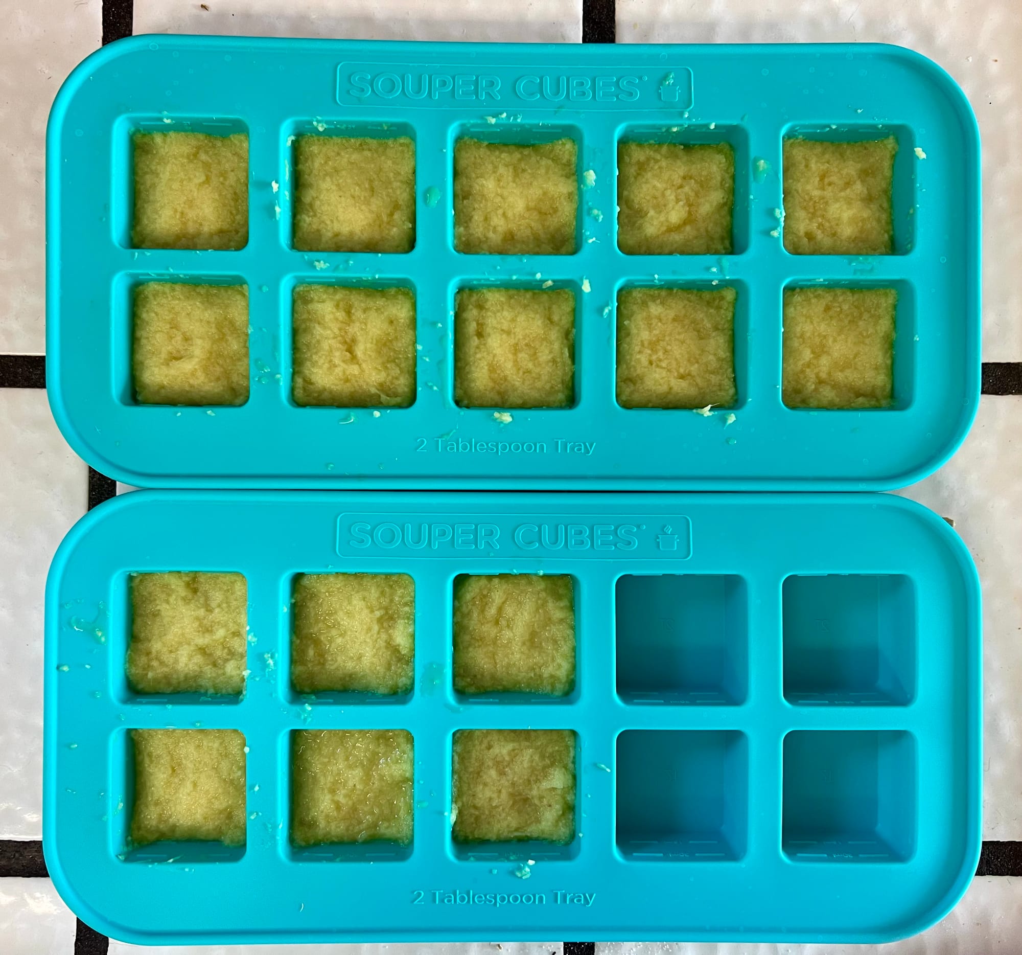 Two silicone trays, they look like ice cube trays. Sixteen of the spots are filled with yellow paste to the halfway mark.