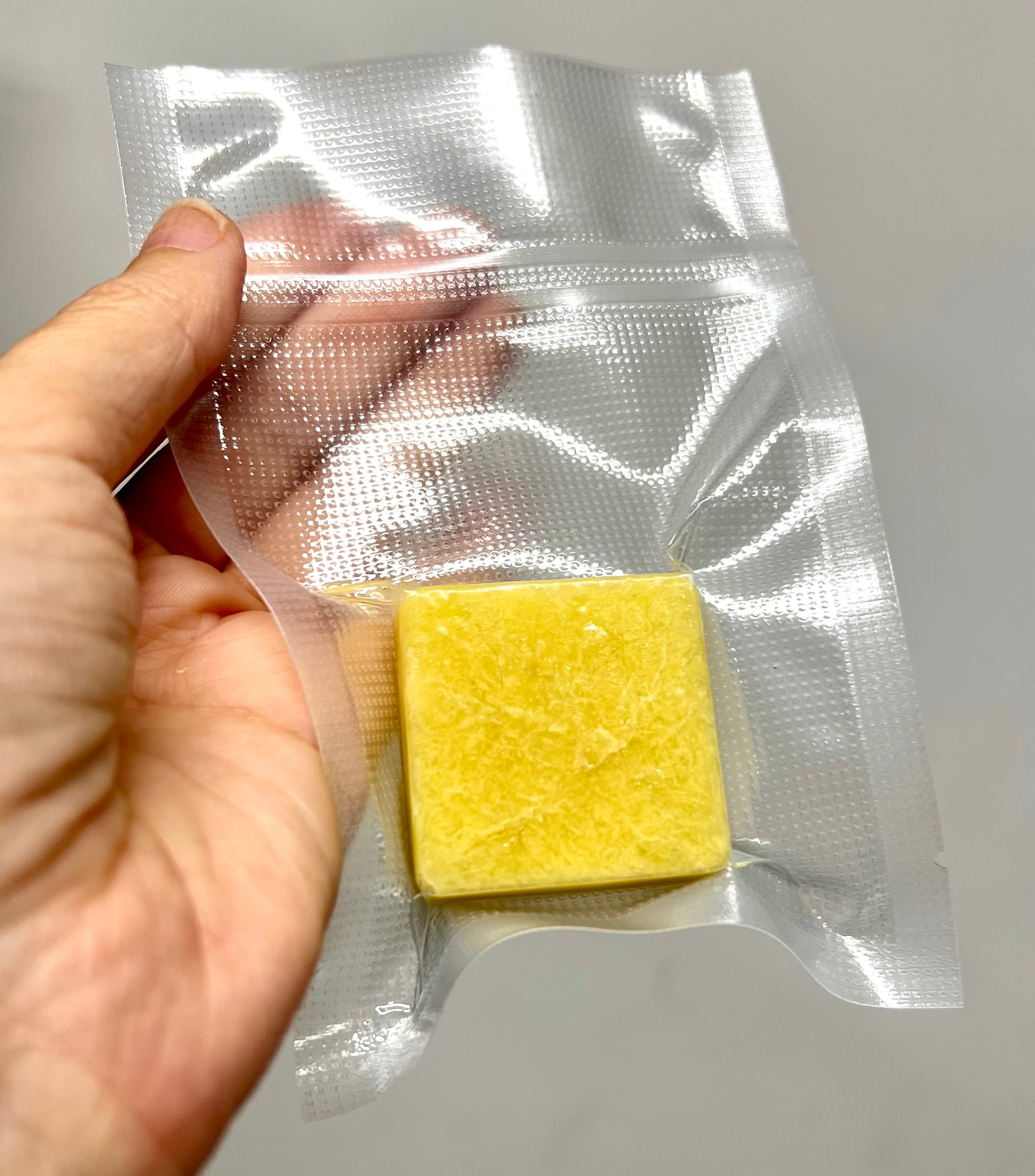 A yellow square, about an inch across, is tightly sealed in a clear plastic bag.