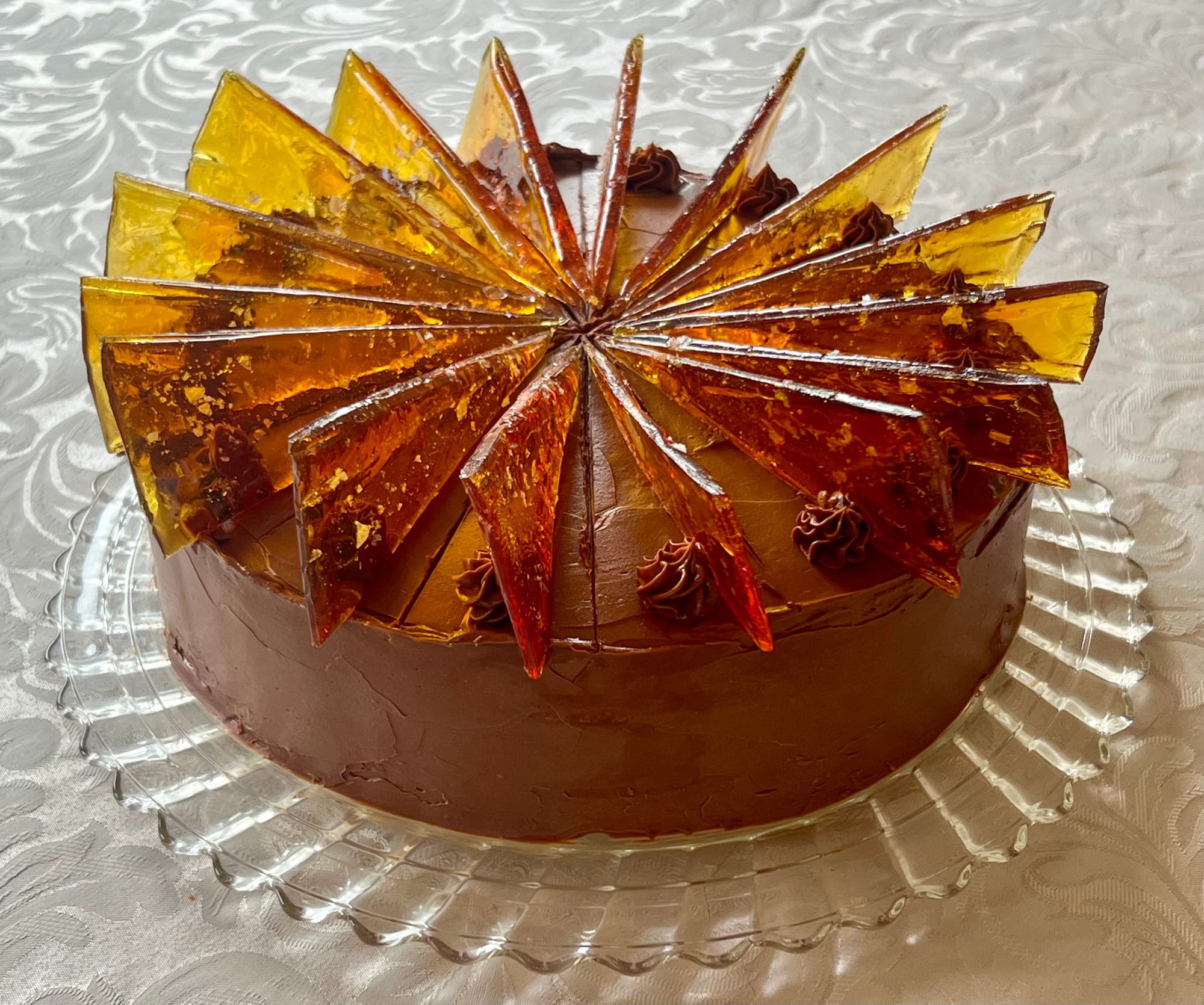 A 9" cake is covered with chocolate icing, and is topped with 18 translucent caramel triangles.