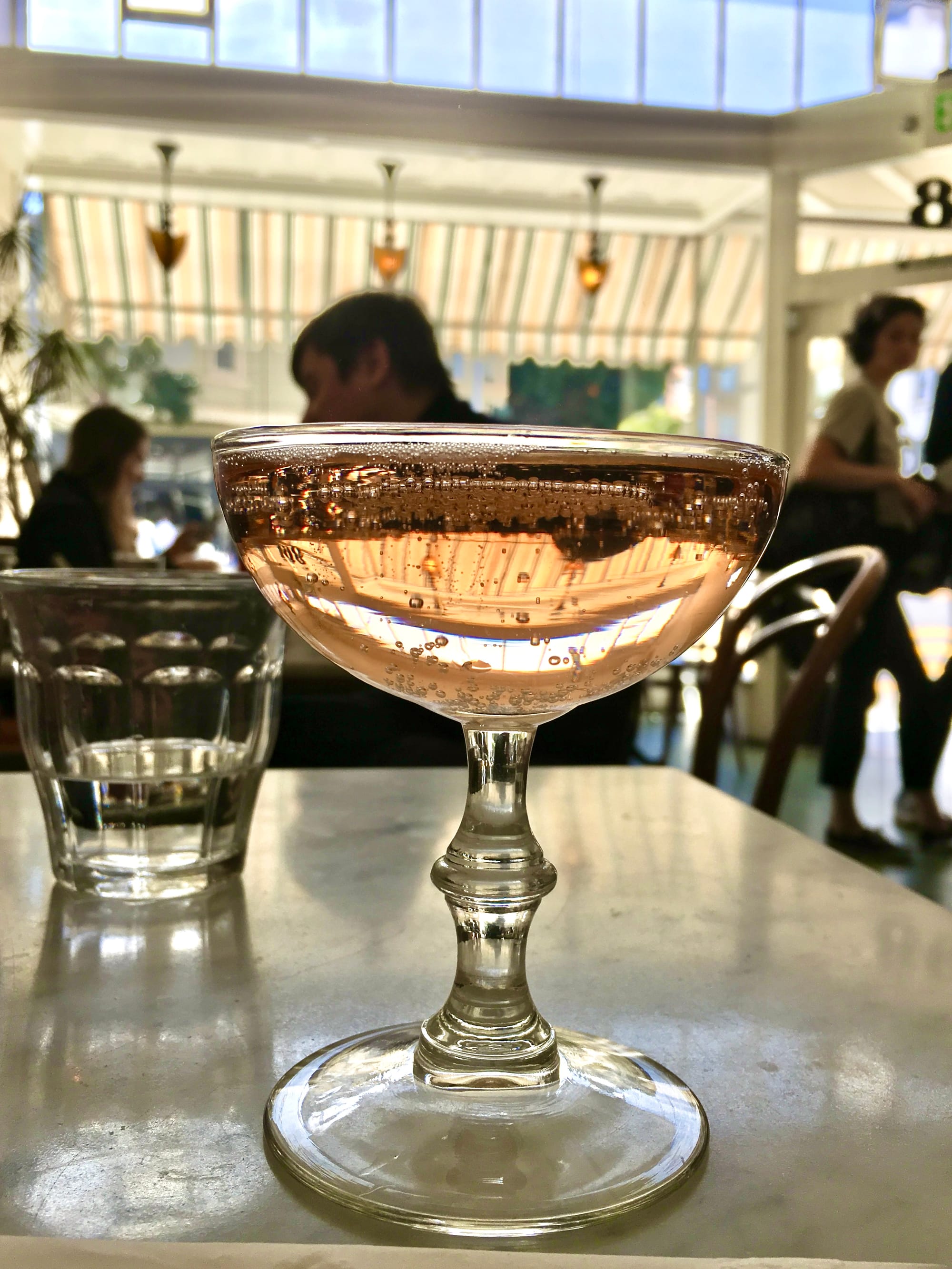 A coupe glass of pink champagne in a cafe.