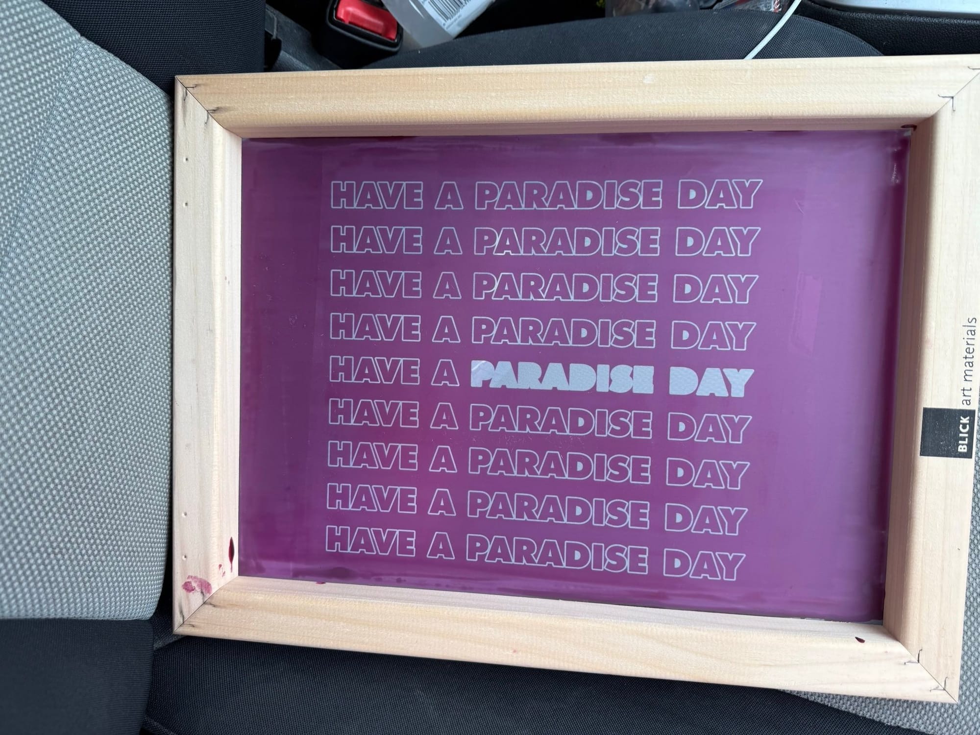 Wood frame with a screenprinting screen set up. The screen is pink with the words "Have a paradise day" repeated in white