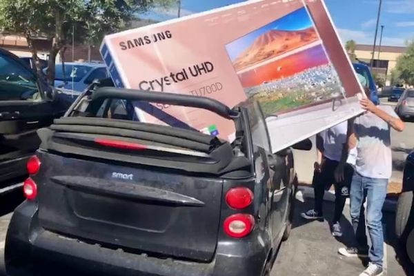 People trying to load a 65 inch tv into a smart car. The tv is 25% wider than the car. They are trying to put it in the back seat with the top down. They look dumb. 