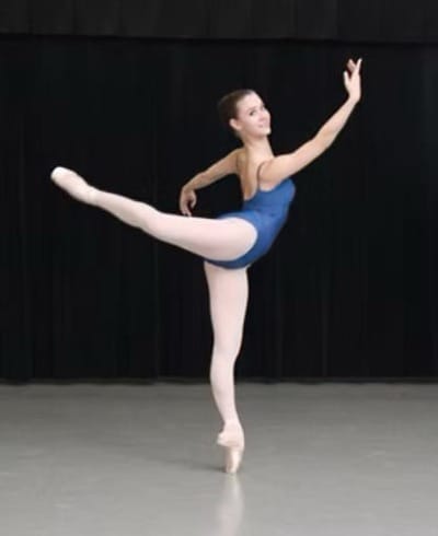 Erin in her ballerina days posing by standing on one toe