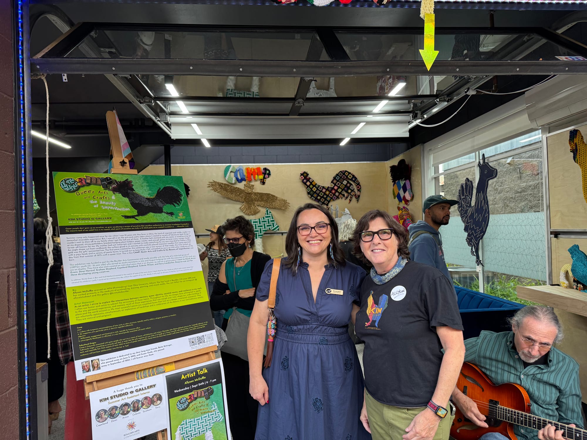 Two people in front of the entrance to an art studio where colorful art projects line the walls.