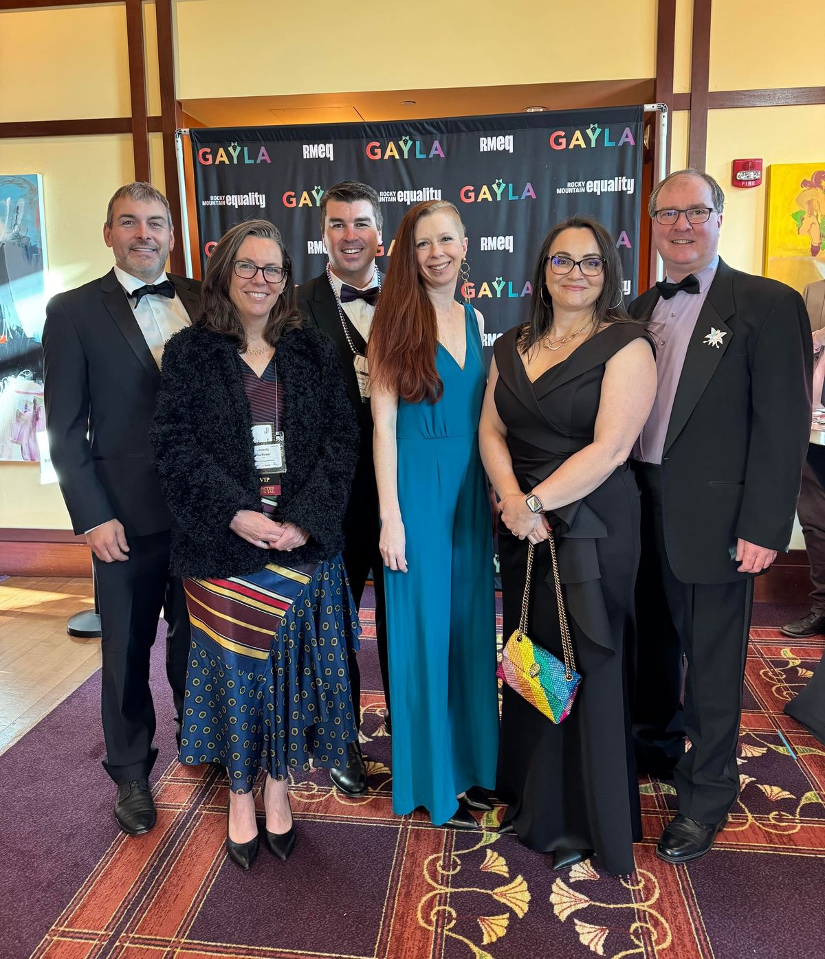 Ryan, Tina, Matt, Lauren, Nicole, and Aaron pose in front of a black backdrop with the Rocky Mountain Equality logo.
